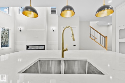 Spacious kitchen island featuring a dual stainless steel sink and a contemporary gold-finish faucet - 204 Falcon Crescent, Leduc, AB 