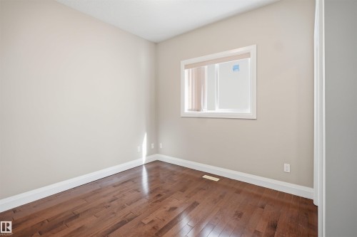 Room featuring wood-finish flooring, neutral wall paint, white baseboards, and a window with white trim - 16807 54 Street, Edmonton, AB - Indoor Photo Showing Other Room