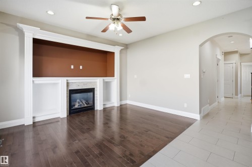 Living area featuring dark wood-finish flooring, a built-in entertainment center with a gas fireplace and shelving, recessed lighting, and a ceiling fan - 16807 54 Street, Edmonton, AB - Indoor Photo Showing Other Room With Fireplace