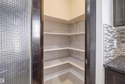 Walk-in pantry featuring corner shelving, light-toned walls, and tile flooring - 16807 54 Street, Edmonton, AB - Indoor With Storage