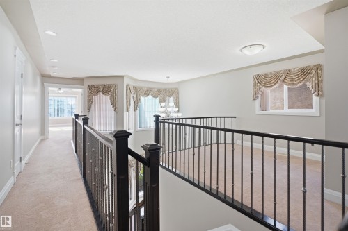 Carpeted landing featuring dark wood newel posts and wrought iron balusters - 16807 54 Street, Edmonton, AB - Indoor Photo Showing Other Room