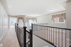 Carpeted landing featuring dark wood newel posts and wrought iron balusters - 