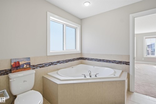 Corner soaking tub with tile surround and mosaic accent - 16807 54 Street, Edmonton, AB - Indoor Photo Showing Bathroom
