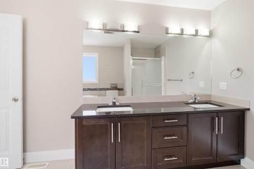 Double vanity with dark wood cabinetry, integrated sinks, and polished chrome hardware - 16807 54 Street, Edmonton, AB - Indoor Photo Showing Bathroom
