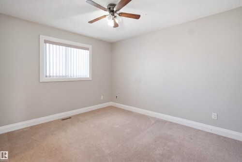 Neutral-toned interior with light tan carpeting and a window featuring vertical blinds - 16807 54 Street, Edmonton, AB - Indoor Photo Showing Other Room