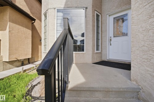 Front entrance with a concrete porch and steps, featuring a white door with decorative glass inserts - 16807 54 Street, Edmonton, AB - Outdoor With Exterior