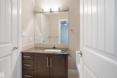Bathroom vanity featuring a single undermount sink, dark wood cabinetry with brushed nickel hardware, and a stone countertop - 16807 54 Street, Edmonton, AB - Indoor Photo Showing Bathroom