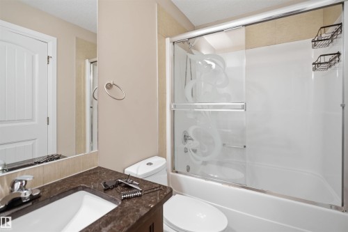 Full bathroom featuring a vanity with an undermount sink, dark stone countertop, and chrome faucet - 16807 54 Street, Edmonton, AB - Indoor Photo Showing Bathroom