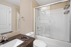 Full bathroom featuring a vanity with an undermount sink, dark stone countertop, and chrome faucet - 