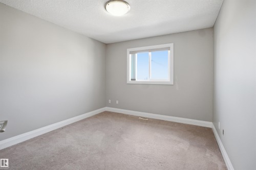 Neutral-toned room featuring a single window with a roller blind, light gray walls, and light-colored carpeting - 16807 54 Street, Edmonton, AB - Indoor Photo Showing Other Room