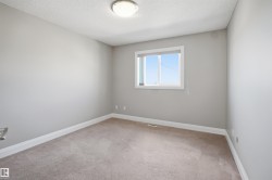 Neutral-toned room featuring a single window with a roller blind, light gray walls, and light-colored carpeting - 
