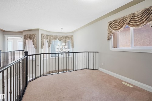 Spacious upper-level landing featuring neutral carpeting and a decorative wrought iron railing - 16807 54 Street, Edmonton, AB - Indoor Photo Showing Other Room