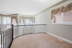 Spacious upper-level landing featuring neutral carpeting and a decorative wrought iron railing - 