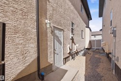 Exterior wall with a textured stucco finish and a white side entry door featuring a decorative outdoor lantern - 