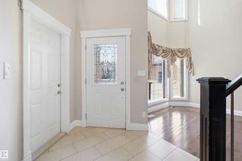 Foyer with decorative leaded glass front door, tile flooring, rich wood-finish flooring, and a dark wood banister - 16807 54 Street, Edmonton, AB - Indoor Photo Showing Other Room