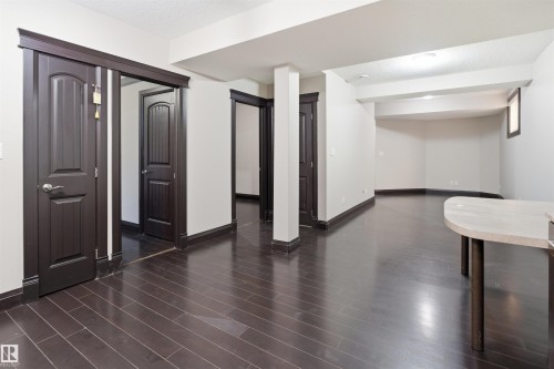 Spacious interior featuring dark wood-finish flooring, white walls, and dark trim throughout - 16807 54 Street, Edmonton, AB - Indoor Photo Showing Other Room