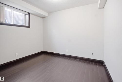 Room featuring dark wood-finish flooring, white painted walls, and a single window with privacy blinds - 16807 54 Street, Edmonton, AB - Indoor Photo Showing Other Room