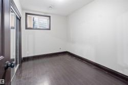 Room featuring dark wood-finish flooring, white walls, and dark trim - 