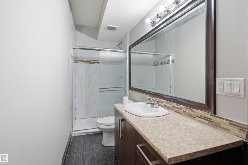 Bathroom featuring a wood-finish vanity with an integrated sink and a textured countertop - 16807 54 Street, Edmonton, AB - Indoor Photo Showing Bathroom