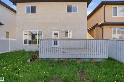 Rear exterior featuring a wooden deck with railing, stucco siding, and a back door with glass paneling - 
