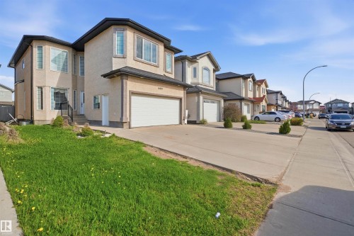 Stucco exterior featuring multiple bay windows, an attached two-car garage, and a concrete driveway - 16807 54 Street, Edmonton, AB - Outdoor With Facade