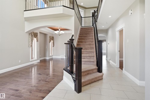 Two-story foyer with a grand staircase featuring dark wood newel posts and iron balusters - 16807 54 Street, Edmonton, AB - Indoor Photo Showing Other Room
