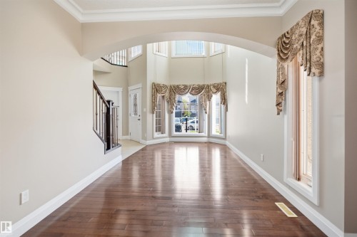 Bright entryway with wood-finish flooring and a grand staircase featuring dark wood newel posts and spindles - 16807 54 Street, Edmonton, AB - Indoor Photo Showing Other Room