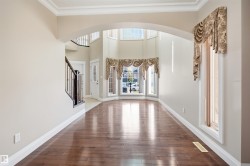 Bright entryway with wood-finish flooring and a grand staircase featuring dark wood newel posts and spindles - 
