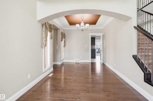 Spacious interior room featuring rich wood-finish flooring, an arched entryway, and white trim - 16807 54 Street, Edmonton, AB - Indoor Photo Showing Other Room