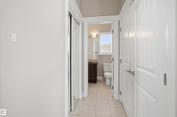 Hallway featuring white panel doors, mirrored closet doors, and light-toned tile flooring - 