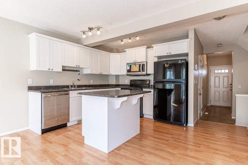 Kitchen featuring white cabinetry, dark countertops, and stainless steel appliances - 39 Vega Avenue, Spruce Grove, AB - Indoor Photo Showing Kitchen