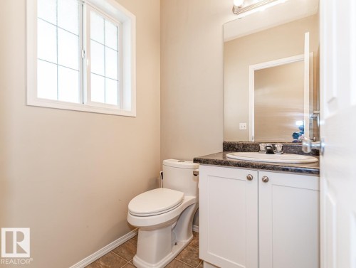 Bathroom vanity featuring white cabinetry, a dark countertop, and an integrated sink with chrome fixtures - 39 Vega Avenue, Spruce Grove, AB - Indoor Photo Showing Bathroom