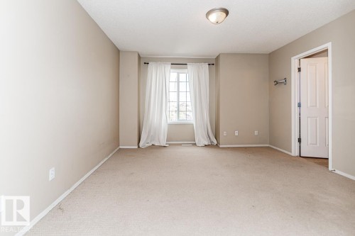 Carpeted room featuring neutral-toned walls, a window with white trim, and a white interior door - 39 Vega Avenue, Spruce Grove, AB - Indoor Photo Showing Other Room