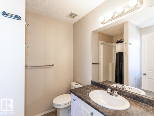 Bathroom featuring a single vanity with an oval sink, a dark patterned countertop, white cabinetry, a toilet, and a stand-up shower with a clear enclosure - 39 Vega Avenue, Spruce Grove, AB - Indoor Photo Showing Bathroom