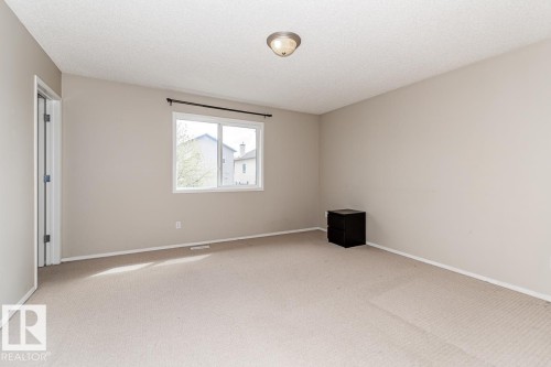 Carpeted room featuring neutral wall tones, a large window with white trim, and a ceiling-mounted light fixture - 39 Vega Avenue, Spruce Grove, AB - Indoor Photo Showing Other Room