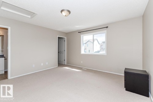 Spacious room featuring neutral carpeting, light-toned walls, and a large window with black curtain rod - 39 Vega Avenue, Spruce Grove, AB - Indoor Photo Showing Other Room