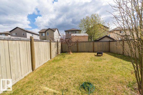 Expansive fenced backyard featuring a fire pit, mature tree, and surrounding privacy fencing - 39 Vega Avenue, Spruce Grove, AB - Outdoor