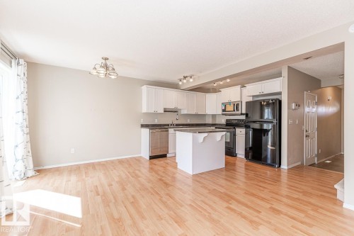 Open-concept kitchen featuring white cabinetry, dark countertops, black appliances, and a central island - 39 Vega Avenue, Spruce Grove, AB - Indoor Photo Showing Kitchen With Double Sink