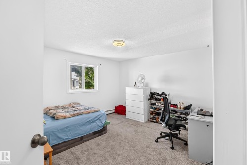Neutral wall paint, textured ceiling, single window with white trim, gray carpeted flooring, and a flush-mount ceiling light fixture - #208 9619 174 St Nw, Edmonton, AB 
