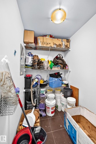 Utility space featuring wire shelving, ceiling-mounted light fixture, and brown floor tiles - #208 9619 174 St Nw, Edmonton, AB 