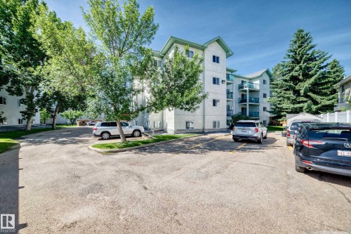 Multi-story residential building with light-colored exterior siding, green roof accents, and individual balconies - #208 9619 174 St Nw, Edmonton, AB 