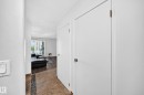 Foyer with tile flooring featuring a mosaic accent strip, leading to a living area with wood-finish flooring and a sliding glass door - #208 9619 174 St Nw, Edmonton, AB 