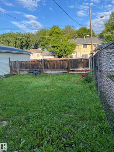Expansive grassy yard area with a chain-link fence on one side and a wood privacy fence on the other - 11938 70 Nw, Edmonton, AB 
