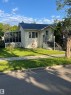 Light yellow siding exterior with a dark shingle roof, front entry steps, a screened-in side porch, and a sidewalk - 11938 70 Nw, Edmonton, AB 