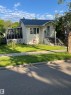 Charming single-story residence with light-colored siding, a dark shingle roof, and a screened-in porch with lattice detailing - 11938 70 Nw, Edmonton, AB 