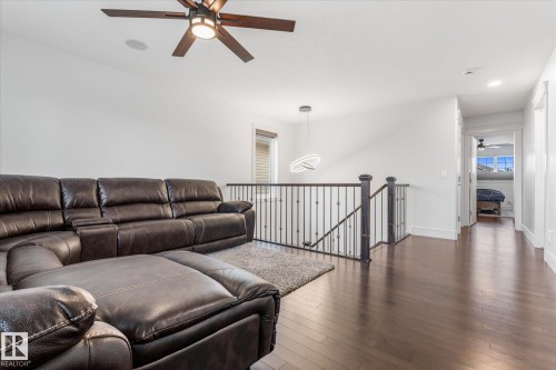 Wood-finish flooring throughout the open hall and seating area, featuring a dark wood and metal spindle railing - 6 Sedona Place, Fort Saskatchewan, AB - Indoor Photo Showing Living Room