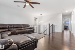Wood-finish flooring throughout the open hall and seating area, featuring a dark wood and metal spindle railing - 