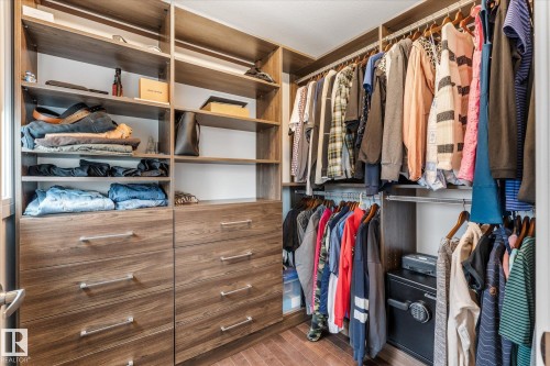 Custom closet system featuring wood-finish cabinetry, integrated shelving, and multiple hanging rods - 6 Sedona Place, Fort Saskatchewan, AB - Indoor With Storage