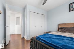 Bedroom featuring wood-finish flooring, light blue walls, and white trim - 