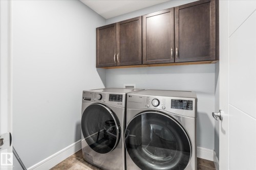 Laundry area featuring dark wood-finish cabinetry, stainless steel appliances, and contrasting light wall paint - 6 Sedona Place, Fort Saskatchewan, AB - Indoor Photo Showing Laundry Room